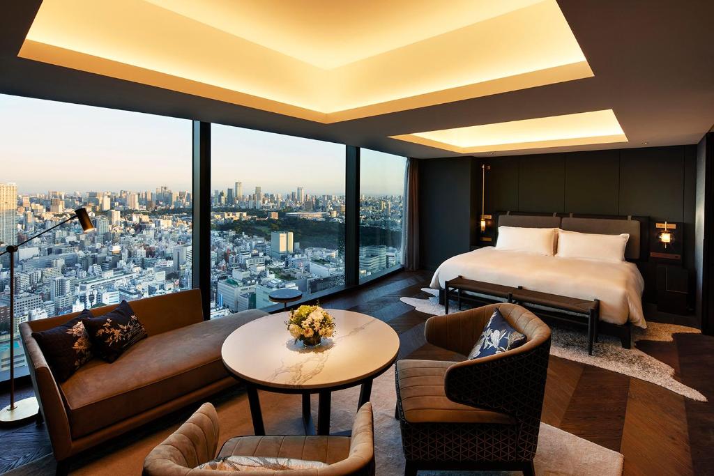 Luxurious hotel room with modern decor, city skyline views, a cozy seating area, and a comfortable king-sized bed.