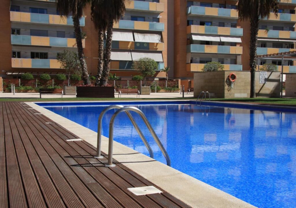Serene swimming pool surrounded by palm trees and modern apartments, perfect for relaxation and leisure activities.