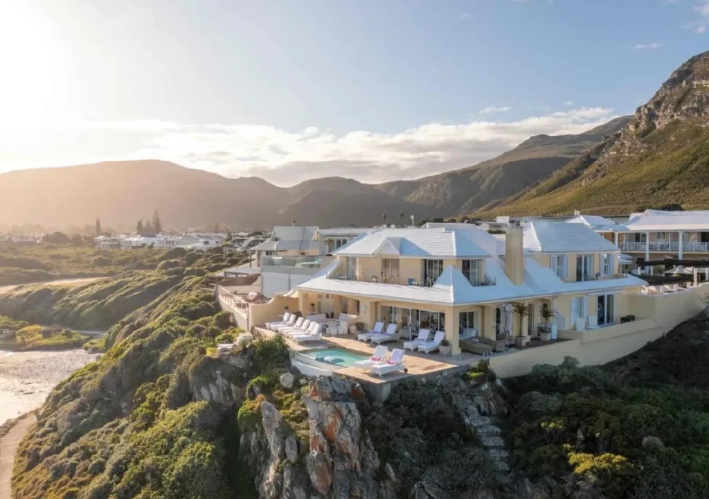 Luxurious villa with a pool overlooking mountains and coastline at sunset, perfect for relaxation and scenic views.