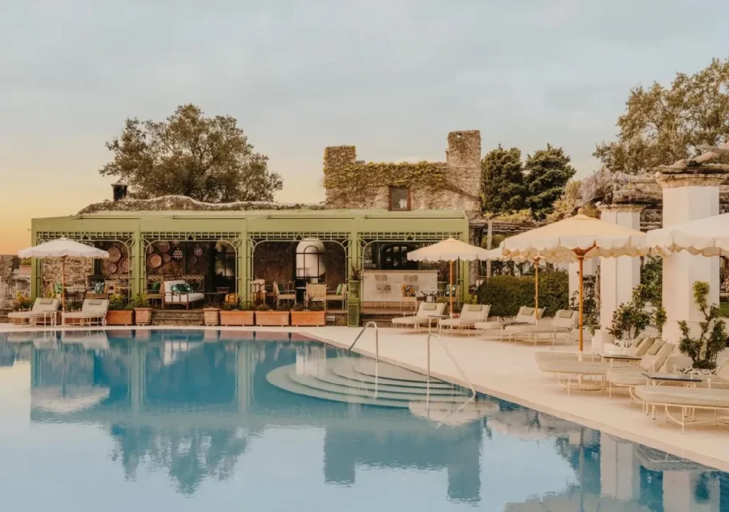 Luxurious villa with a shimmering pool and elegant seating, surrounded by lush greenery at sunset. Serenity and style.