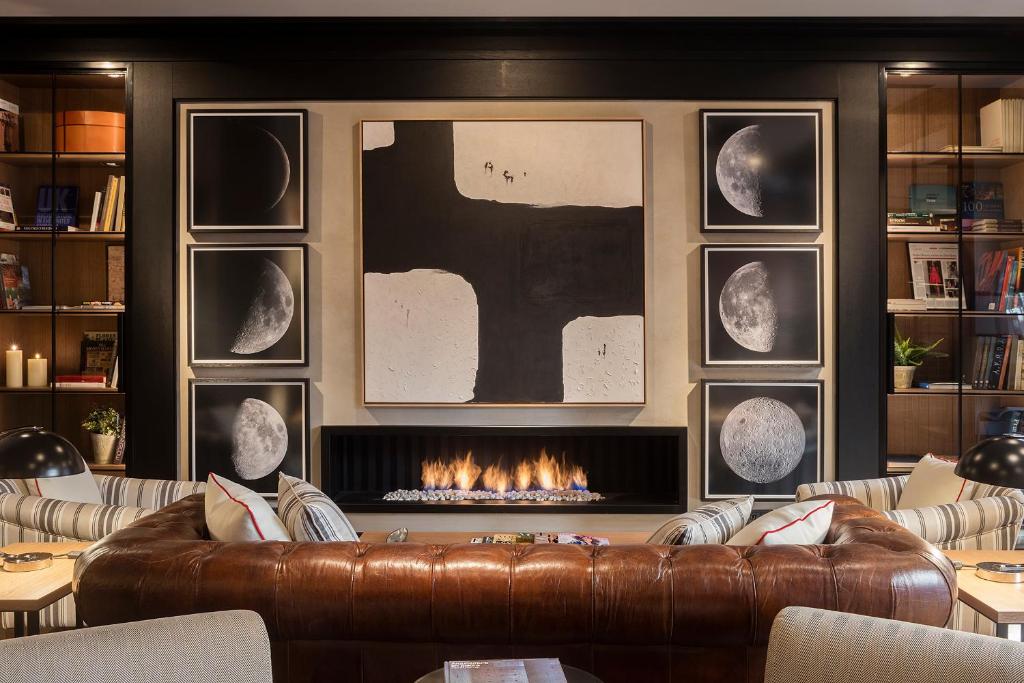 Modern living room with leather couch, abstract art, moon phase prints, and a sleek fireplace, creating a cozy atmosphere.