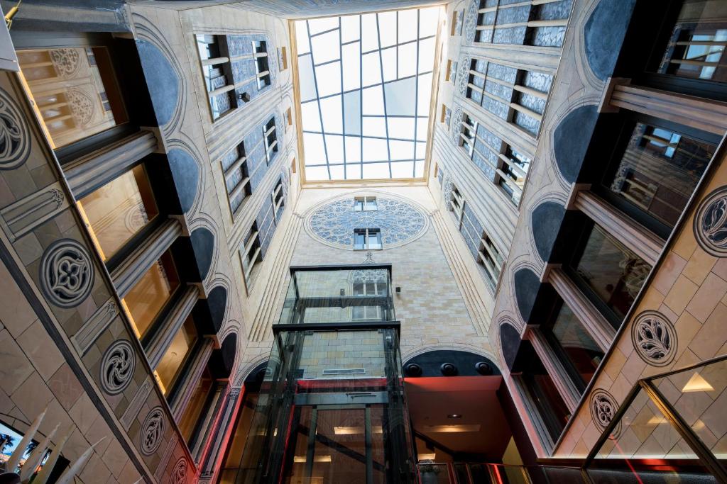 Alt text: Looking up at a stunning interior atrium with decorative walls and a glass ceiling, showcasing architectural details.