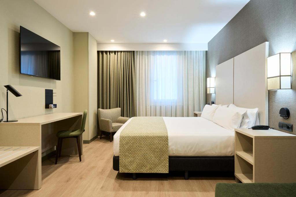 Modern hotel room with a king-size bed, desk, TV, and cozy seating area. Ideal for relaxation and business stays.