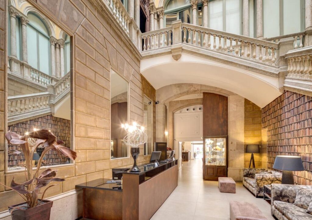 Elegant hotel lobby featuring luxurious decor, a reception desk, and decorative bookshelves in a bright, welcoming space.