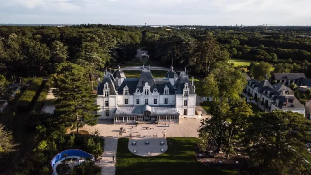 Aerial view of a grand chateau surrounded by lush greenery and elegant landscaping, showcasing classic architectural beauty.