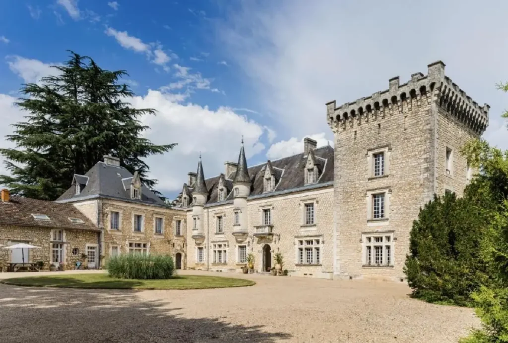 Stunning historical chateau with turrets and lush grounds under a blue sky, perfect for a luxury getaway or event.