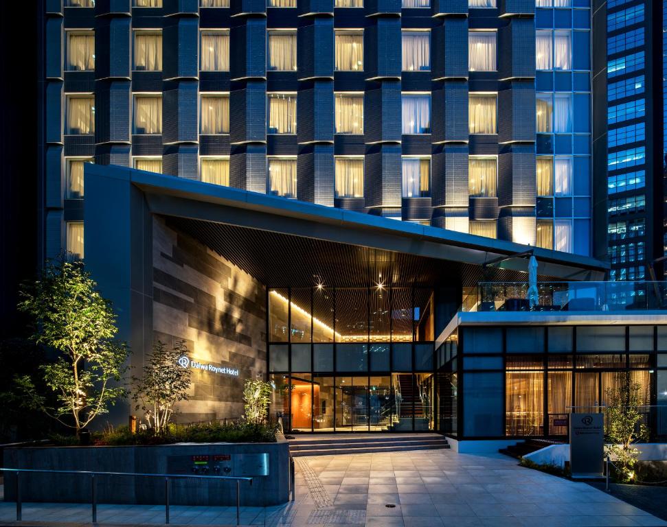 Modern urban hotel entrance at night, featuring sleek architecture and warm lighting, inviting guests in.