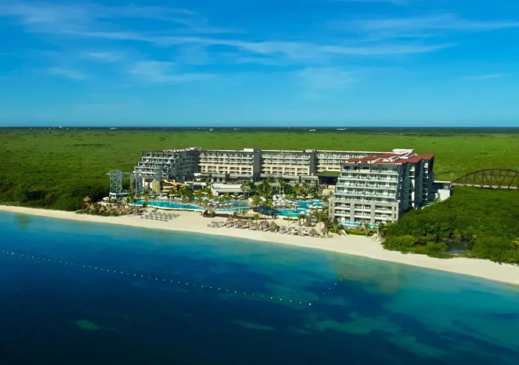 Aerial view of a luxurious beachfront resort with pools, pristine sand, and lush greenery in the background. Perfect getaway!