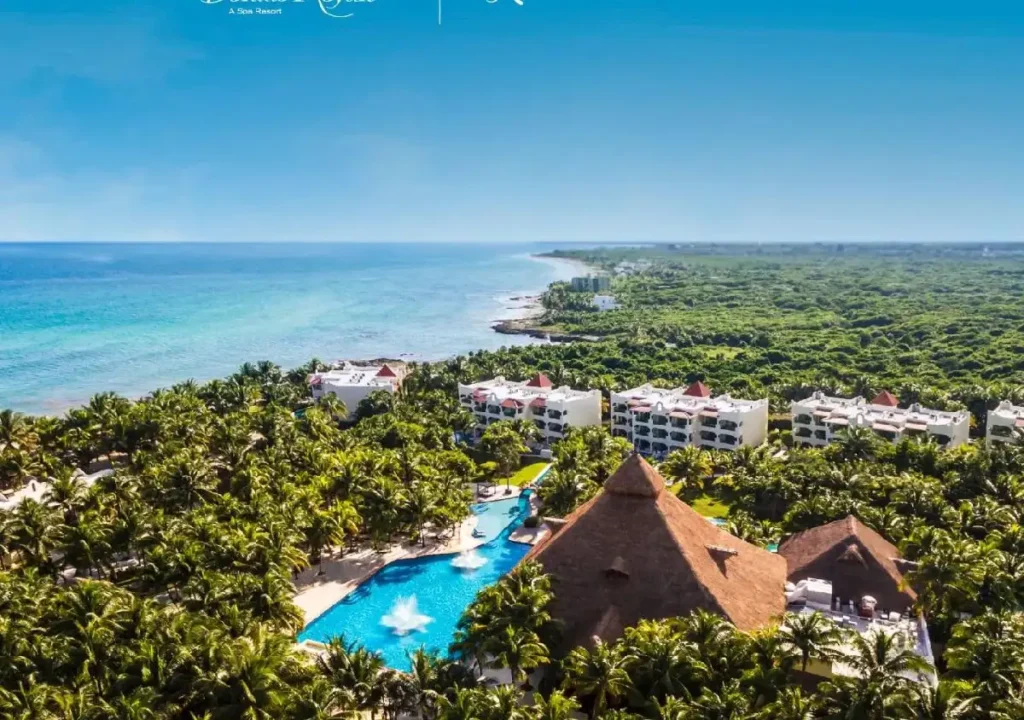 Aerial view of a tropical resort with lush greenery, pools, and ocean, perfect for vacations and relaxation.