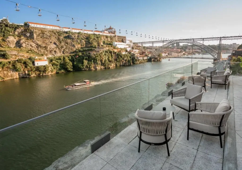 Riverside terrace with seating, overlooking scenic views of Porto, Portugal, and the iconic Dom Luís I Bridge.