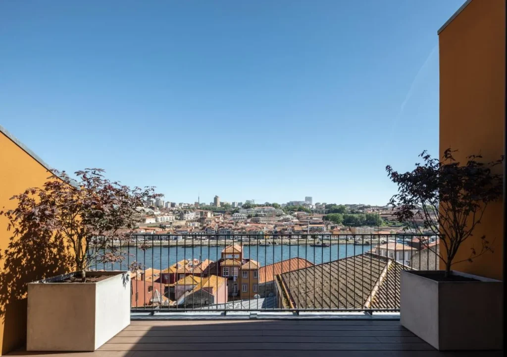 Stunning balcony view overlooking a river, colorful buildings, and clear blue sky in an urban landscape.