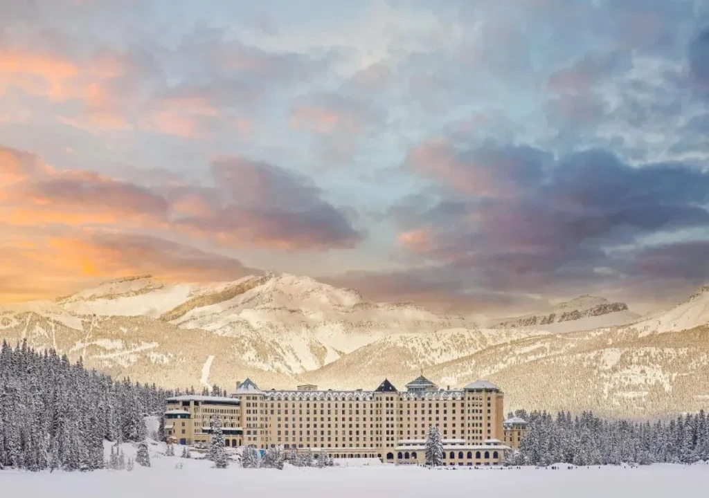 Majestic snowy hotel surrounded by mountains at sunset, perfect for winter vacations and retreats.