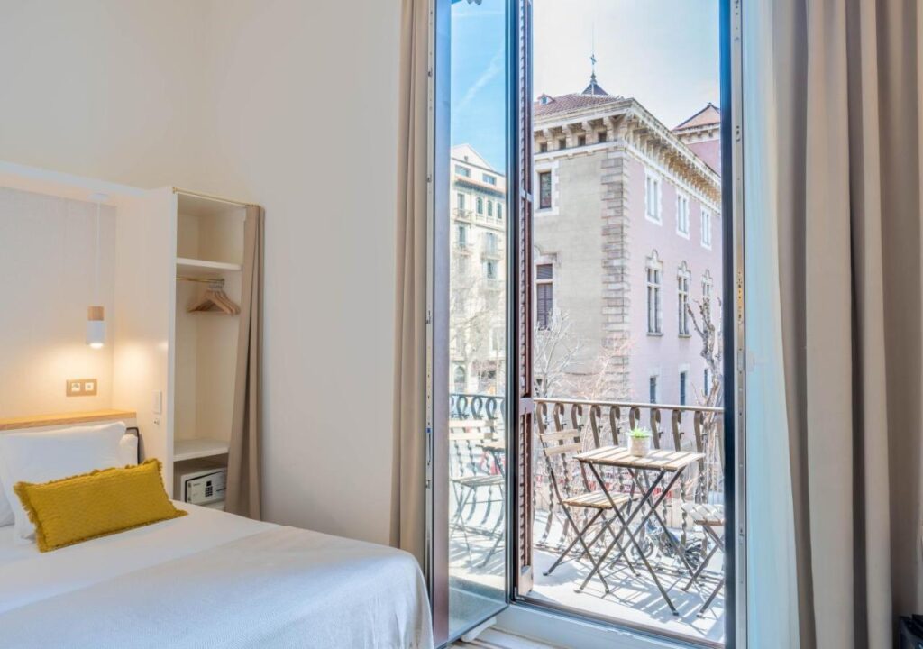 Cozy hotel room with a balcony view, featuring modern decor and natural light, ideal for a relaxing stay.
