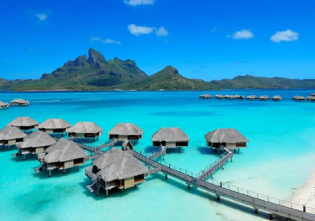 Tropical lagoon with overwater bungalows, stunning blue water, and lush mountains in the background. Ideal for vacations.