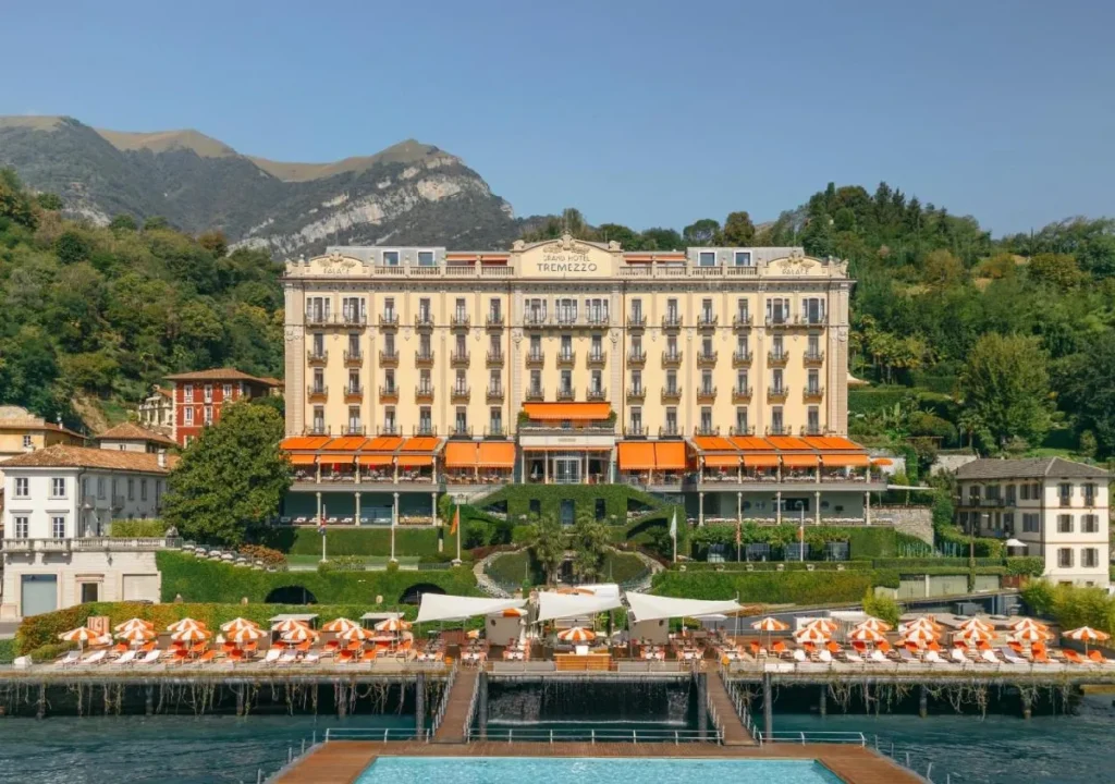 Grand Hotel Tremezzo overlooking Lake Como, featuring stylish lounges, sunbeds, and lush gardens against mountain backdrop.