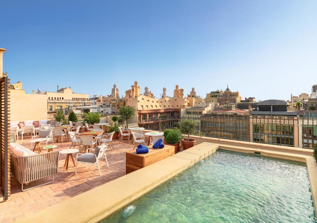 Rooftop terrace featuring a swimming pool and lounge seating with city views on a sunny day. Perfect for relaxation.