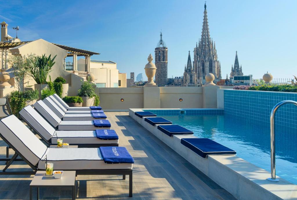 Rooftop pool with lounge chairs and city view, featuring a stunning cathedral in the background under a clear sky.