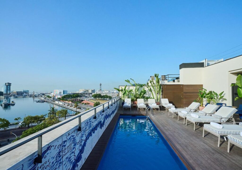 Rooftop pool with lounge chairs overlooking the harbor and clear blue sky, perfect for relaxation and stunning views.
