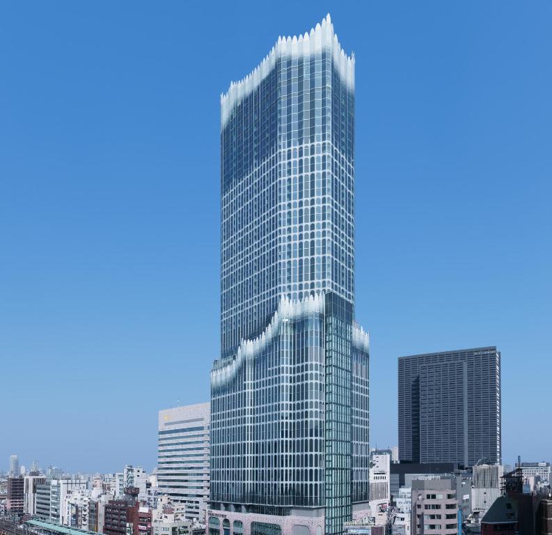 Modern skyscraper with unique design standing against a clear blue sky, highlighting urban architecture in the city.