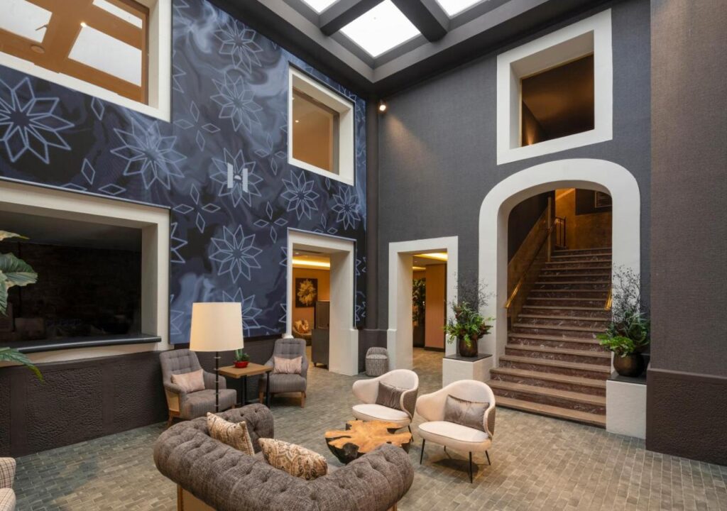 Modern lobby with elegant seating, artistic wall design, and stairs leading to upper levels, creating a welcoming atmosphere.