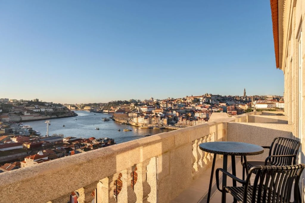 Stunning view of Porto from a balcony, showcasing the Douro River and vibrant cityscape under clear blue skies.