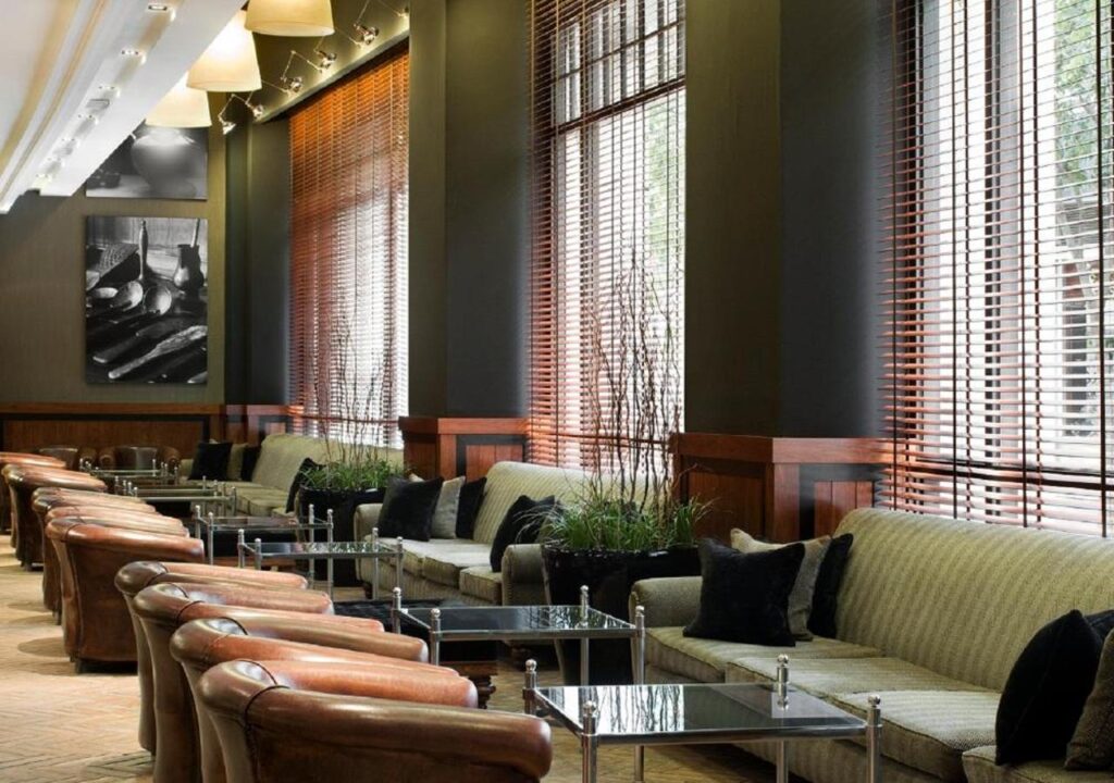 Modern lounge with comfortable seating, wooden accents, and natural light filtering through blinds. Perfect for relaxation.