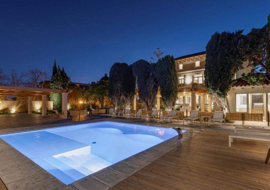 Luxurious outdoor pool area at twilight, surrounded by lush greenery and elegant lounge chairs, perfect for relaxation.