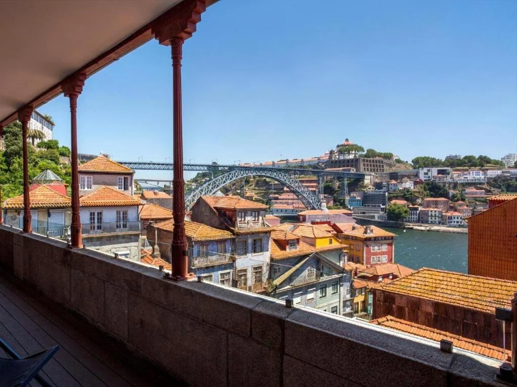 Scenic view of Porto, Portugal, showcasing colorful rooftops and the iconic Dom Luís I Bridge against a clear blue sky.