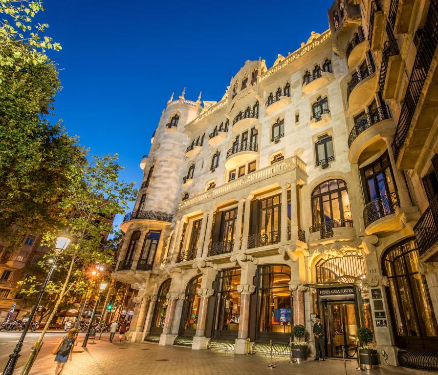 Exterior view of Hotel Casa Fuster at dusk, showcasing its beautiful architecture and vibrant street scene in Barcelona.