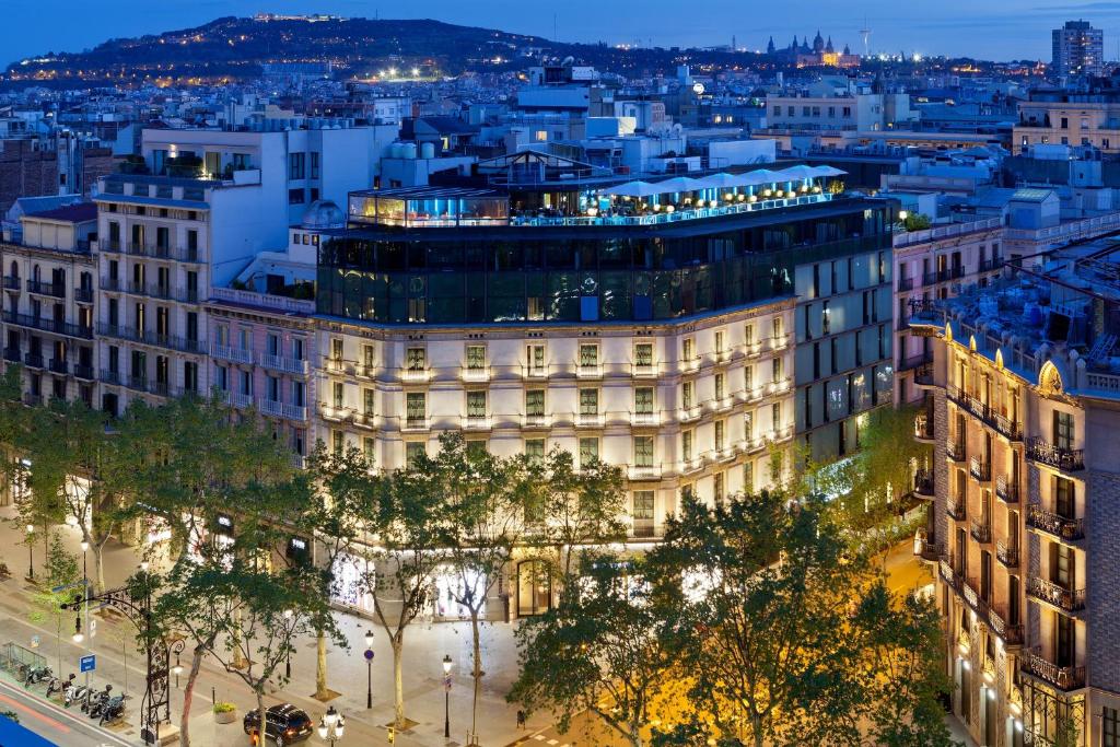 View of a beautifully lit building in Barcelona at dusk, showcasing city architecture and vibrant urban life.