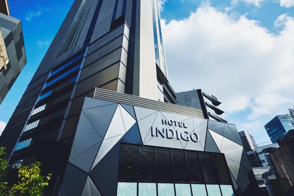 Modern exterior of Hotel Indigo, showcasing geometric design against a blue sky in an urban setting. Ideal for travelers.