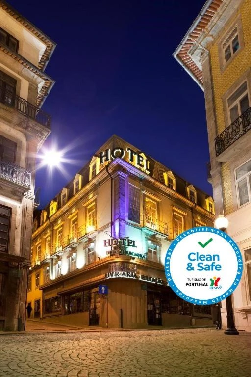 Illuminated hotel in Portugal at night with Clean & Safe certification symbol, showcasing a charming urban atmosphere.