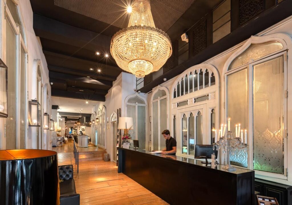 Elegant hotel lobby with a grand chandelier and intricate decor, featuring a welcoming front desk area.