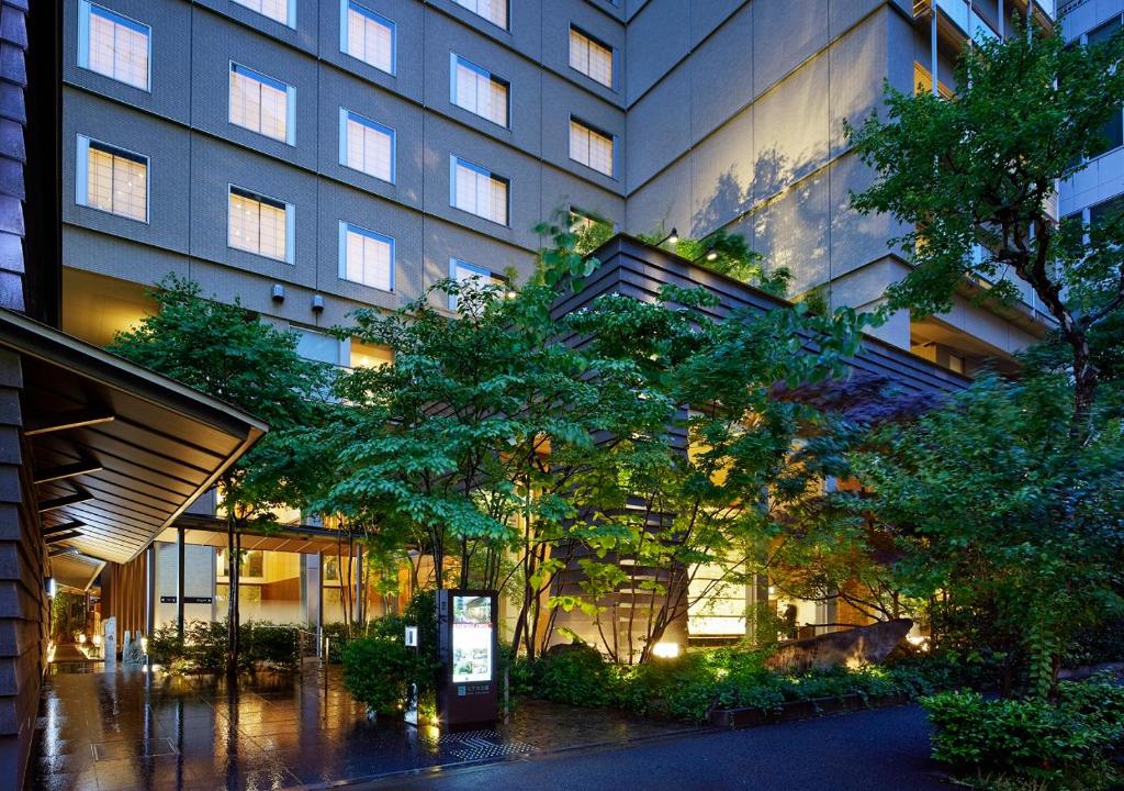 Modern hotel entrance surrounded by lush greenery, illuminated at dusk, showcasing a welcoming atmosphere.