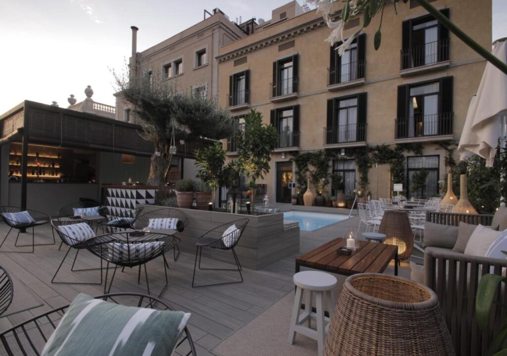 Tranquil hotel terrace with a pool, stylish seating, and greenery, perfect for relaxation and outdoor gatherings.