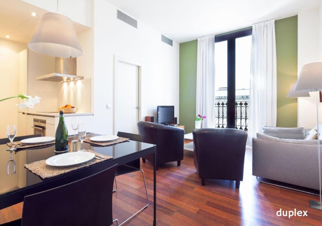 Modern duplex living area with dining setup, kitchen view, and balcony, perfect for relaxing and entertaining.