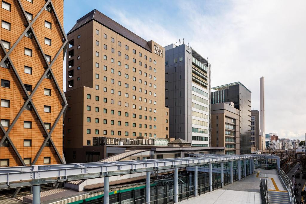 Urban landscape featuring modern buildings and a train station in a city setting, with a clear sky and architectural details.