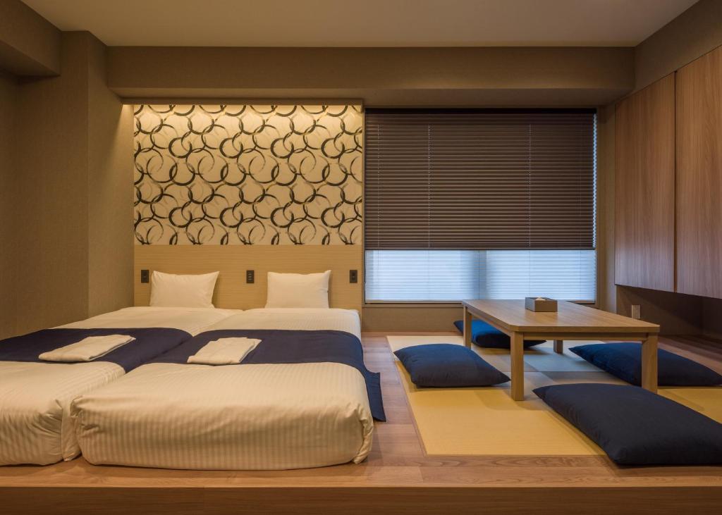 Modern Japanese-style room featuring twin beds and a traditional seating area with tatami mats and cushions.