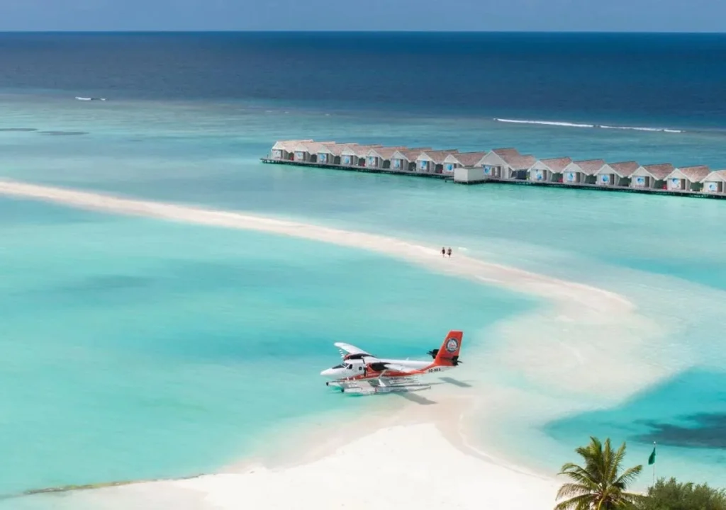 Seaplane landing at a serene beach resort, surrounded by turquoise water and luxurious overwater bungalows.
