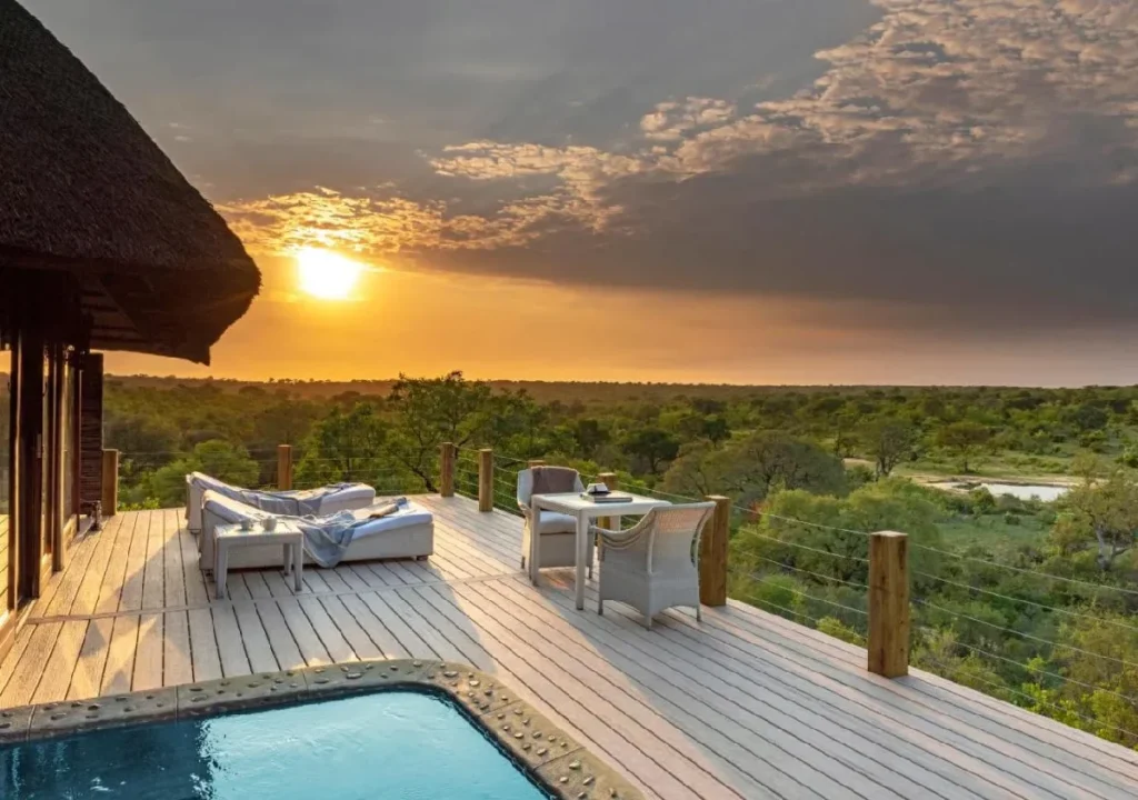Sunset view from a luxurious deck overlooking lush greenery and a serene pool, perfect for relaxation and nature escape.