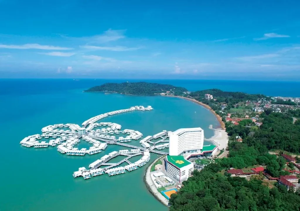 Aerial view of a luxury resort near the beach, surrounded by turquoise waters and lush greenery. Ideal for vacations.