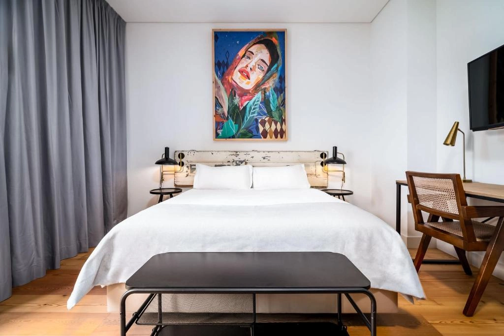 Modern hotel room featuring a stylish bed, artwork, and inviting decor with a cozy workspace. Perfect for relaxation.