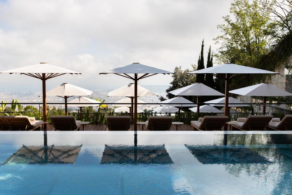 Luxurious poolside view with lounge chairs and umbrellas overlooking a scenic landscape and cloudy sky. Perfect for relaxation.