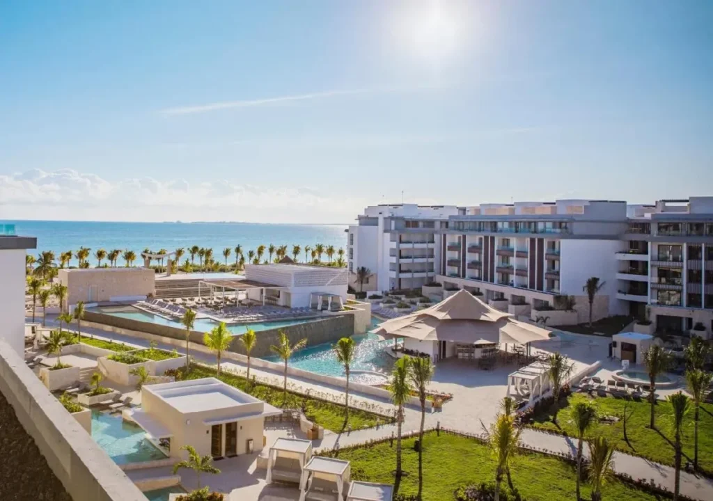 Stunning beachfront resort in sunny paradise with pools, palm trees, and luxurious accommodations overlooking the ocean.