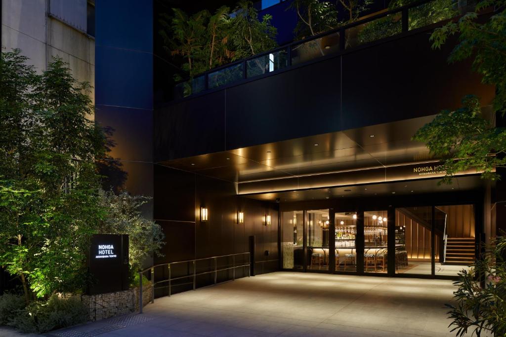 Elegant entrance of Nohga Hotel in Akihabara, Tokyo, featuring modern architecture and lush greenery at night.