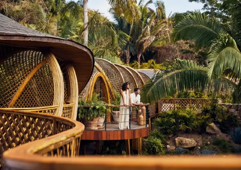 Couple enjoying a scenic view from a modern bamboo structure surrounded by lush tropical greenery. Perfect for eco-friendly getaways.