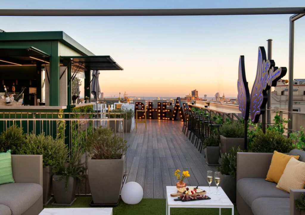 Rooftop lounge with elegant seating, vibrant decor, and a stunning sunset view over the city skyline. Perfect for gatherings.