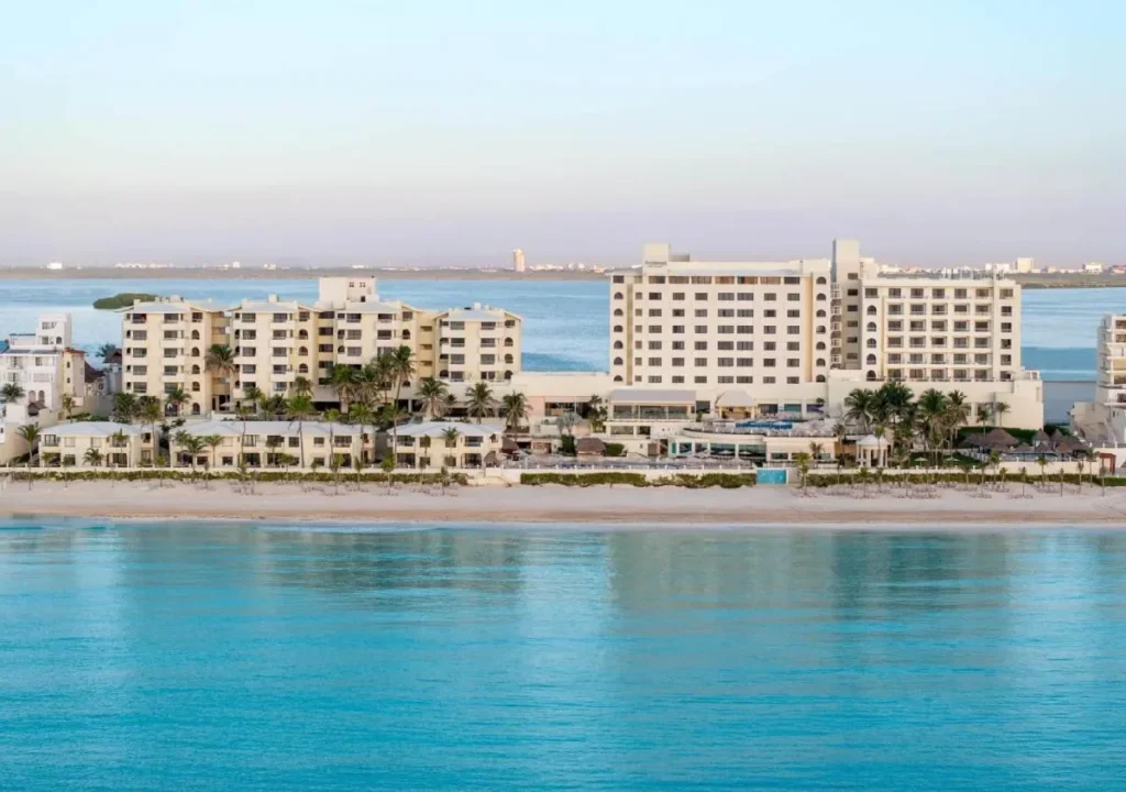 Beachfront resort with modern architecture, surrounded by palm trees and calm turquoise waters. Perfect vacation getaway.