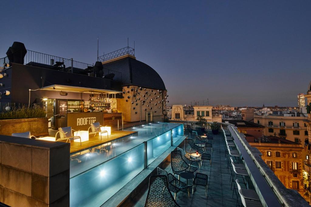 Luxurious rooftop terrace with a bar, pool, and stunning city views at twilight, perfect for relaxation.