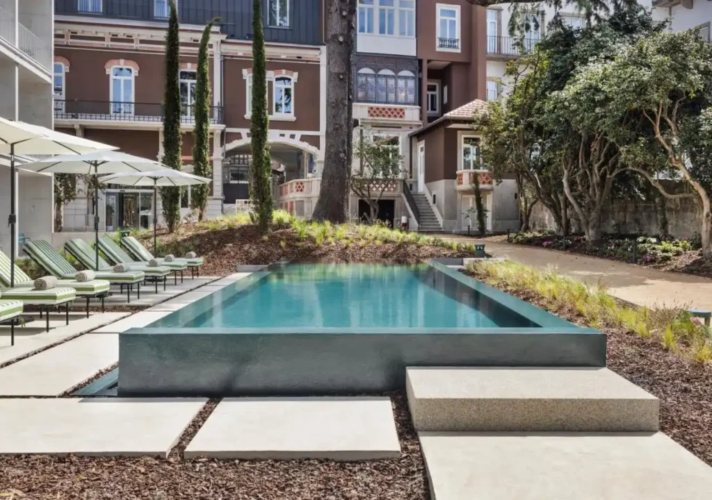 Modern pool surrounded by lush landscaping and lounge chairs in a stylish outdoor space.